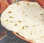 A close-up of a cooked Fresh Flour Tortilla from one of the two packages of 10, placed on a plate.